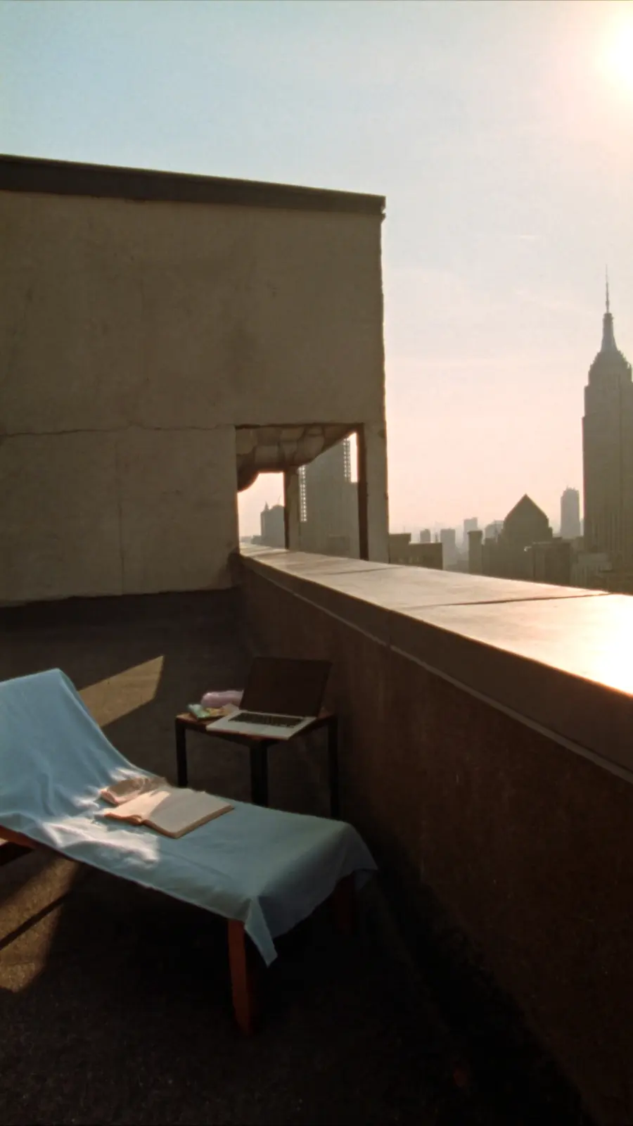 A rooftop workspace with a laptop and open book at golden hour
